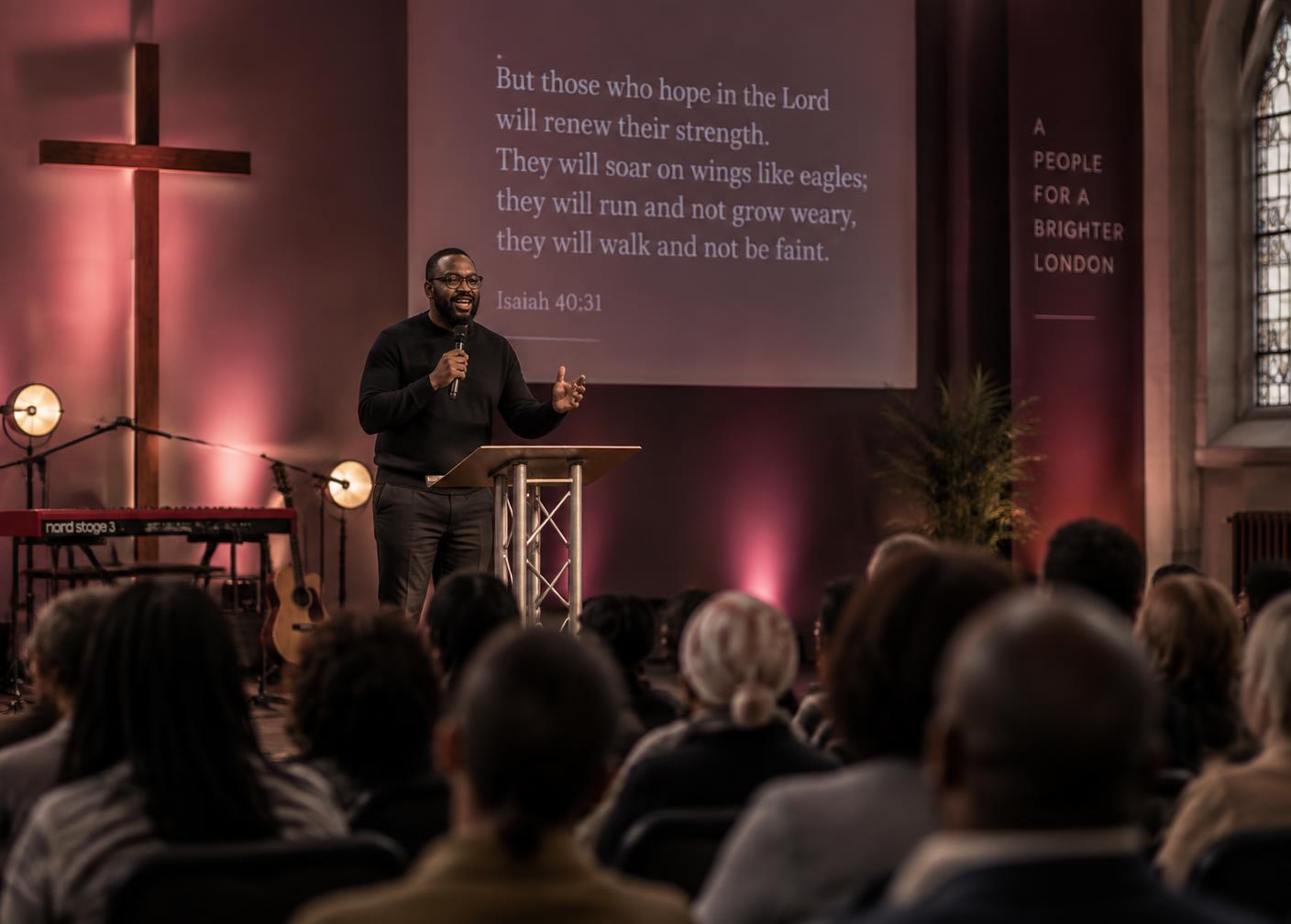 A preacher speaking while scripture is projected behind him
